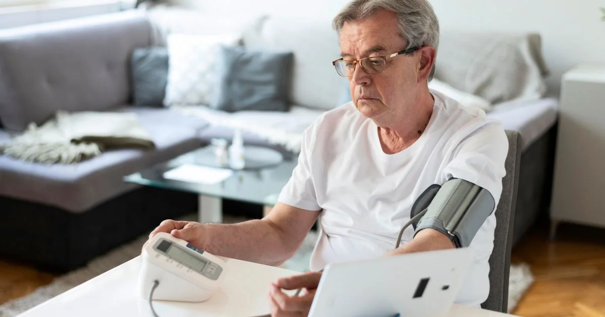 Senior man measuring his blood pressure with digital monitor at home
